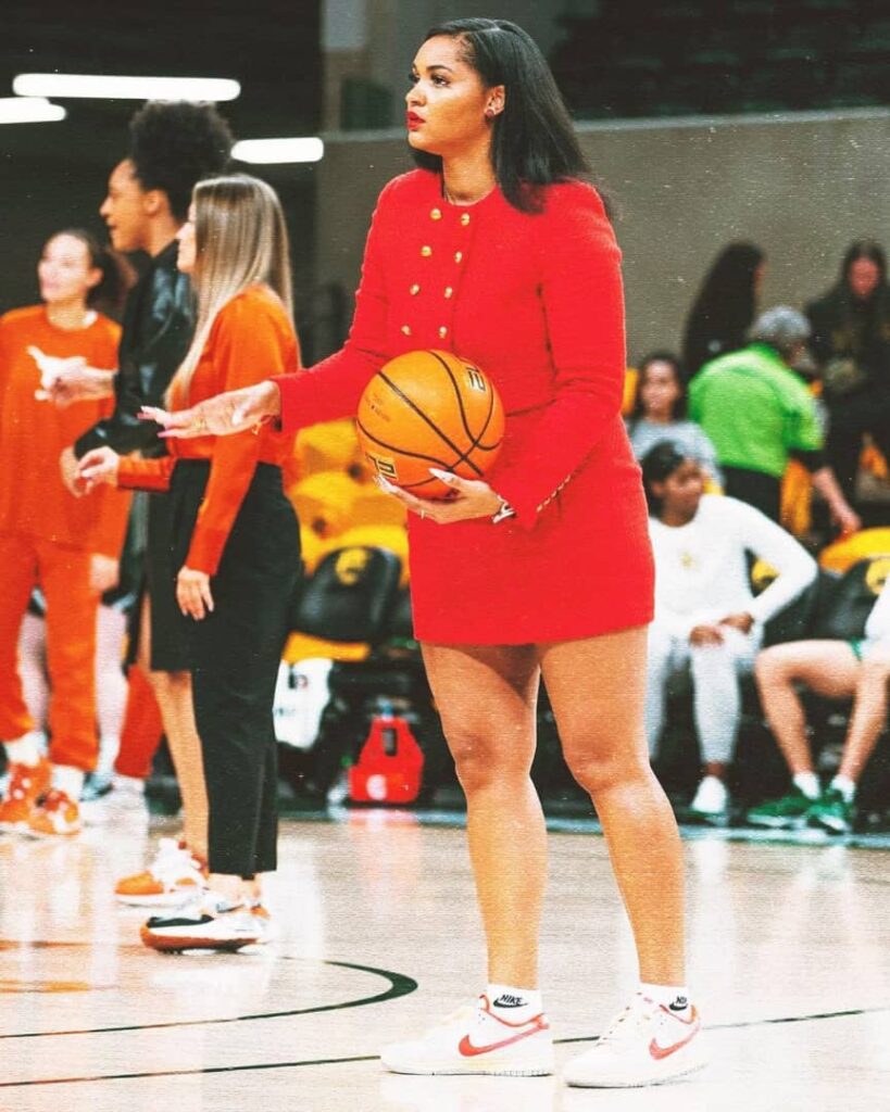 The coach in a red coloured skirt and jacket while handling a basketball
Credit:- Sydney Carter|Instagram