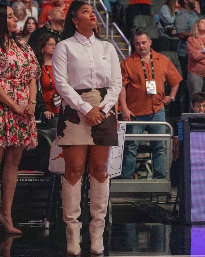 Sydney in a white shirt and cream and brown patterned skirt along with a knee length boots.
 Photo Credit:- Sydney Carter| Instagram.